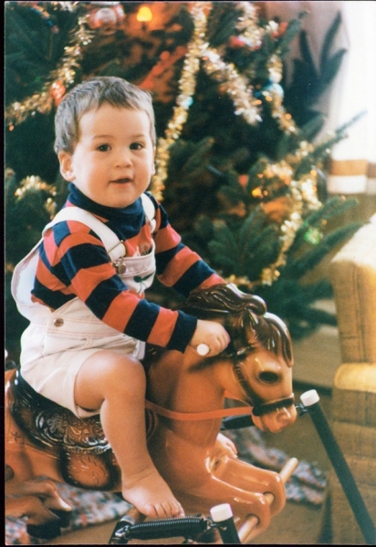 Austin on a bouncey horse in front of the tree